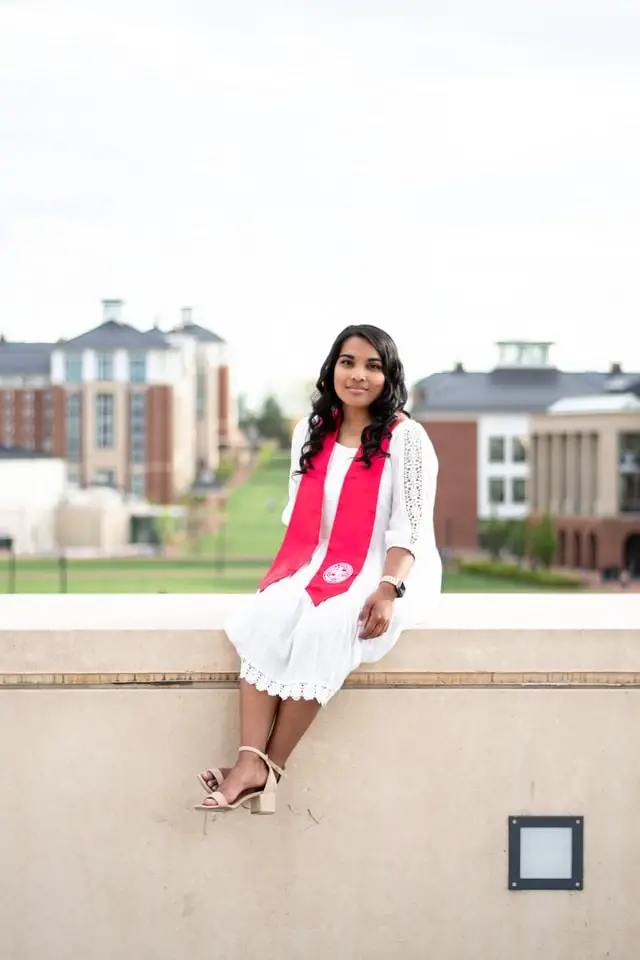 Woman sitting on a ledge wearing university graduation attire