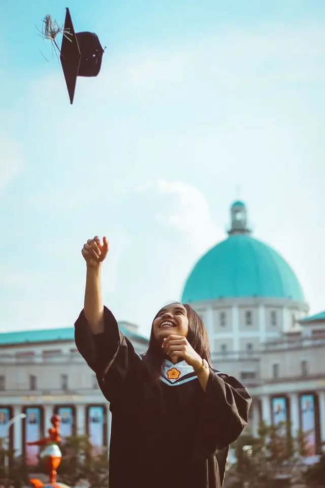 Woman throwing her hat in the air at her college graduation