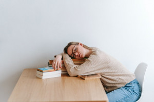 Student lying on her books in a library