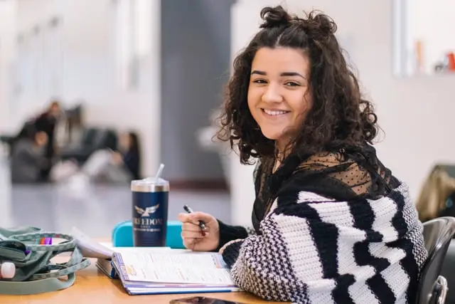 Girl writing notes in her book about the pros and cons of student loans